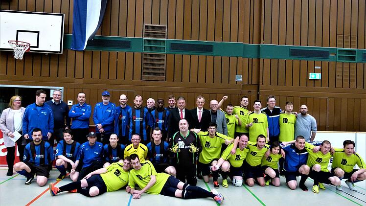 Die beiden Endspielteilnehmer,  die Hochfr&auml;nkischen Werkst&auml;tten Hof (blaue Trikots) und Sieger Wefa Ahorn (gelbe Trikots). Mit im Bild BFV-Bezirksvorsitzender Thomas Unger (hinten, Dritter von links),   Landrat Klaus Peter S&ouml;llner, BLSV-Kreisvorsitzender Lothar Seyfferth und  Harry Wei&szlig; (Mitte von links) von der Sparkasse Kulmbach-Kronach, der den Wanderpokal &uuml;berreichte. Foto: Werner Rei&szlig;aus