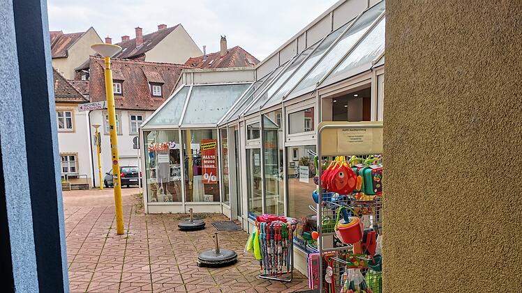 Ein Gesch&auml;ft mit der Aufschrift "Schlussverkauf" im Schaufenster. Davor befindet sich ein St&auml;nder mit buntem Kinderspielzeug. Das Geb&auml;ude hat ein Glasdach.