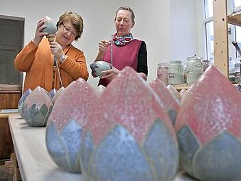Christa Schlegelmilch und Töpfermeisterin Marianne Kurg-Schütz stecken die tönernen Blütenkugeln auf die Stangen. Die Blütenknospen sind Einzelstücke und wurden angefertigt als besonderes Geschenk und Würdigung für diejenigen, die sich um den "Tag der offenen Gartentüre" 2014 in Zeil verdient gemacht hatten. Die Würdigung wurde am Freitag beim "Zeiler Abend" ausgesprochen.  Foto: Brigitte Krause