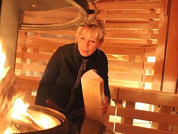 Cordula Reichardt befeuert den Kamin in der Erdhügelsauna. Foto: Thomas Heuchling