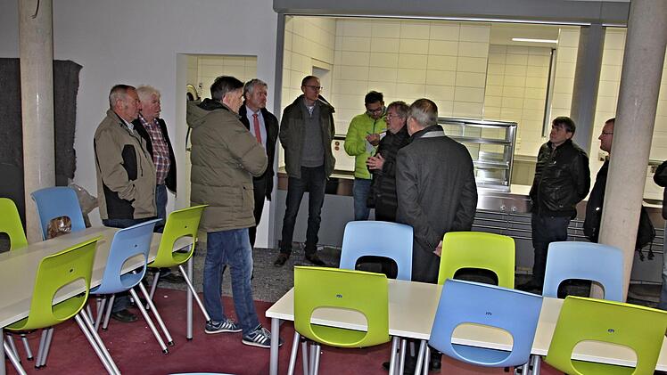 Im Dezember soll die neue Mensa teilweise genutzt werden können. Der Bauausschuss mit Bürgermeister Jürgen Hennemann (Vierter von links) ließ sich vor Ort vom Architekten Günther Pollach (Siebter von links), hier im künftigen Speisesaal mit der Anrichte im Hintergrund, informieren.Will