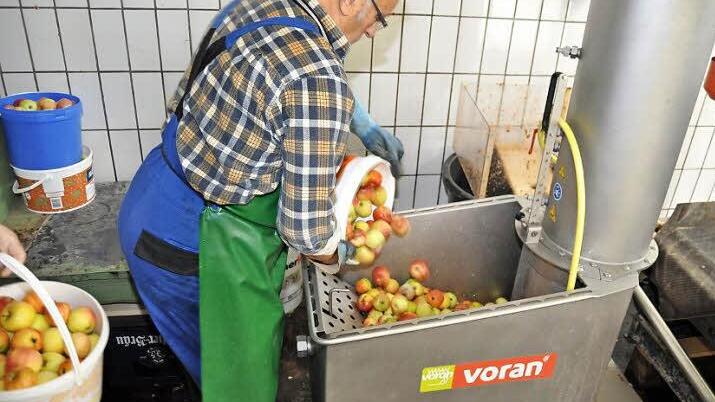 Kelterwart Georg Petterich schüttet das Obst für die nächste Charge in den Waschbehälter. Über eine Transportschnecke wird es nach dem Waschen in die rechts oben angebaute Rätzmühle befördert und dort zerkleinert. Foto: Ingrid Kohles