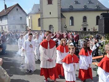 Ministranten und Geistliche beim Einzug zum festlich geschmückten Altarpodium. Im Hintergrund der Musikverein Glosberg und der Gesangverein "Liederkranz" Haig. Foto: Karl-Heinz Hofmann
