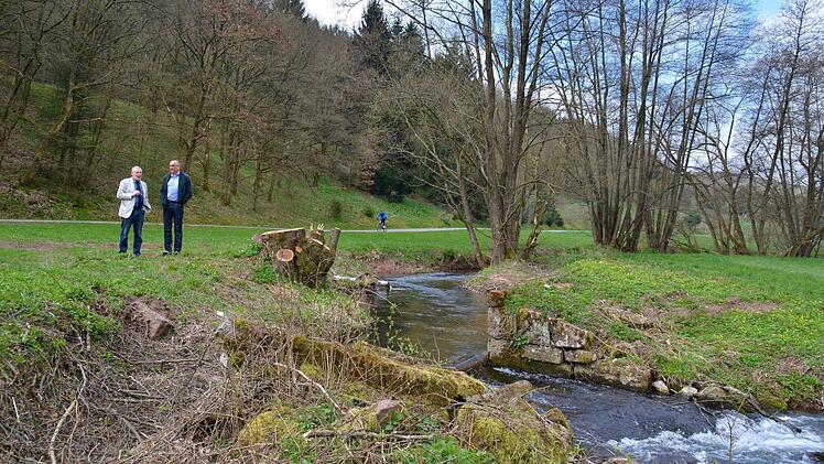 Dieses Wehr liegt auf Frauenrother Gemarkung und soll ebenfalls rekonstruiert werden. Auf dem Bild ist gut erkennbar, wie nah der Radweg an der Aschach vorbeiführt. Hier erklärt Bürgermeister Waldemar Bug (links, Markt Burkardroth) seinem Kollegen Andreas Sandwall (Markt Bad Bocklet) dass auch Wasser um das Wehr herumgeführt wird.  Foto: Kathrin Kupka Hahn