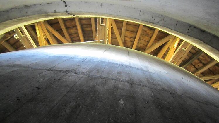 Blick von unten auf den Wasserbehälter aus Beton und das Dachgebälk.