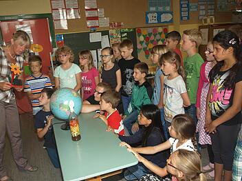 Energie ist großes Thema unserer Zeit und aller Menschen. Vor allem praktische Anregungen erarbeiteten die Drittklässler der Grundschule Oerlenbach mit Agraringenieurin Brigitte Krieglstein (links), hier mit Windrad, Globus und Flasche mit Biomasse. Foto: Stefan Geiger