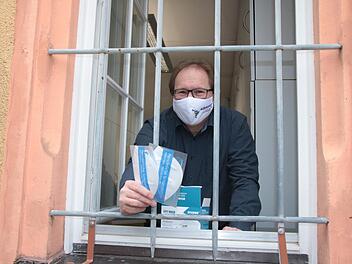 Auch wenn die Fenster des Hammelburger Pfarrbüros vergittert sind, kommen die Masken von Herzen: Pfarrer Thomas Eschenbacher bei der Ausgabe.  Foto: Ralf Ruppert