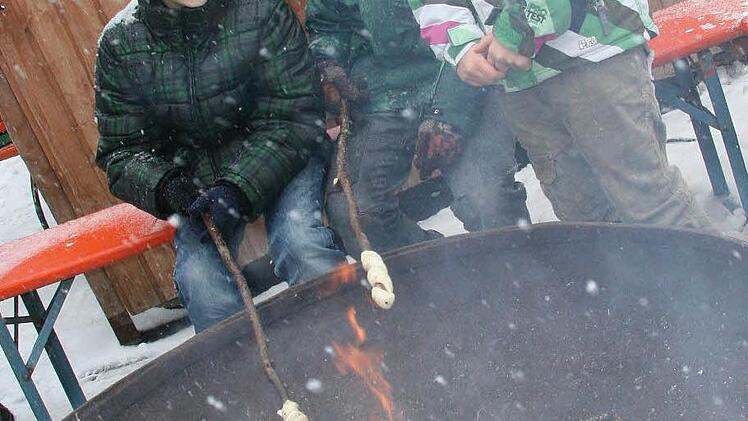 Nick Erhardt (11), Leon Würffel (10) und Lilly Würffel (7) haben einen Platz an der Feuerschale ergattert und grillen Stockbrot.
