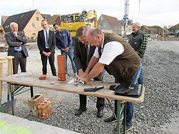 Bürgermeister Werner Stöcker (rechts) und Landrat Helmut Weiß rollen unter den Augen der Norma-Vertreter Zeitungen und Broschüren für die Zeitkapsel zusammen.  Foto: privat