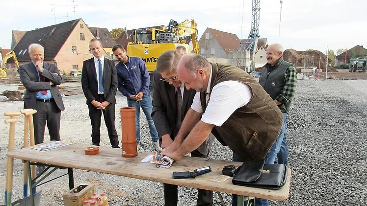Bürgermeister Werner Stöcker (rechts) und Landrat Helmut Weiß rollen unter den Augen der Norma-Vertreter Zeitungen und Broschüren für die Zeitkapsel zusammen.  Foto: privat