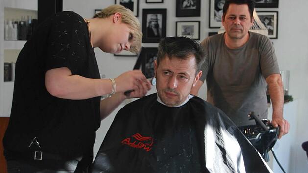 Friseurgesellin Luiza Paul frisiert Stammkunde Velimir Stevanovic - ihr Chef Holger Maas beobachtet das Ganze. Foto: Andreas L&ouml;sch