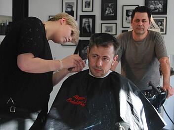 Friseurgesellin Luiza Paul frisiert Stammkunde Velimir Stevanovic - ihr Chef Holger Maas beobachtet das Ganze. Foto: Andreas Lösch