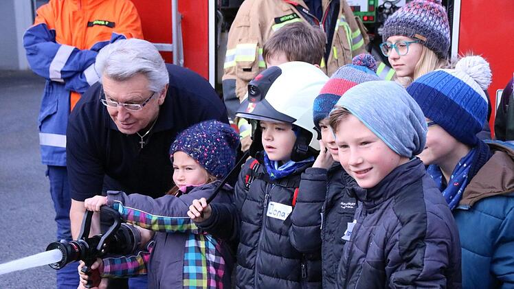 Gabriel Finger von der Haßfurter Feuerwehr zeigt den Kindern den "Erstangriff" im Brandfall: Löschwasser wird aus dem 5000-Liter-Tank des Feuerwehrautos gepumpt und zur Flammeneindämmung genutzt.