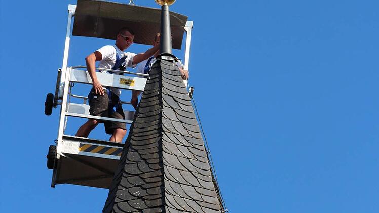 Handwerker befestigen die Turmzier an der Kapelle.