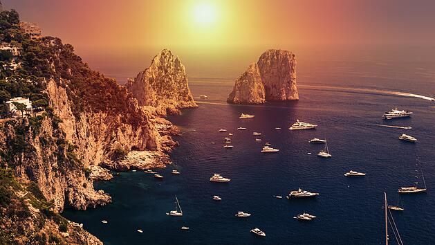 Faraglioni rocks in amazing sunrise ight visible from Giardini di Augusto in Capri, Italy. Focus on stone rocks. Sunrise is a photomanipulation