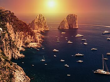 Faraglioni rocks in amazing sunrise ight visible from Giardini di Augusto in Capri, Italy. Focus on stone rocks. Sunrise is a photomanipulation