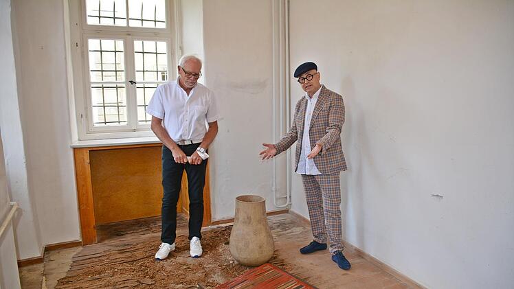 Der Künstler Thomas Pfarr aus Münnerstadt zeigt Rudolf Weigand hier das Buch der Offenbarung. Er verweist dabei auf die Verarbeitung mit rund 1000 Jahre altem Eichenholz, Eisen, Kunstharz und auf eine Klangurne, gefertigt von Heike Kleinlein. Foto: Friedrich.
