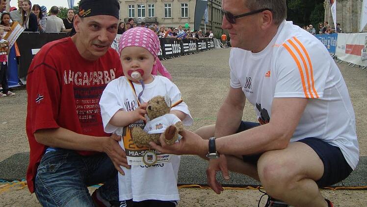 Mia-Sophie war mit 21 Monaten die jüngste Teilnehmerin beim Bambini-Lauf. Da überreichte SÜC-Abteilungsleiter Berthold Lendner persönlich den Teddy, den alle kleinen Läufer bekamen. Foto: Astrid HEss
