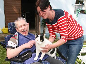Bewohner Andy (38) freut sich, als Einrichtungsleiterin Claudia Mai ihm den Hauskater Karl-Heinz auf den Schoß setzt.  Foto: Sonja Adam