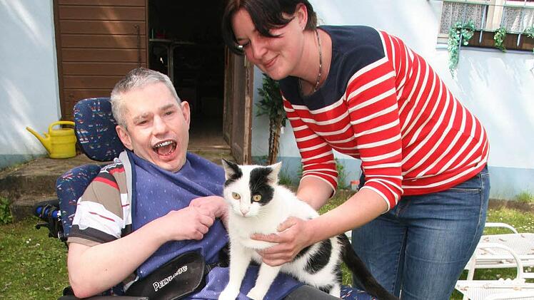 Bewohner Andy (38) freut sich, als Einrichtungsleiterin Claudia Mai ihm den Hauskater Karl-Heinz auf den Schoß setzt.  Foto: Sonja Adam