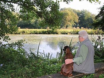 Der Eissee am Musikschulweg ist ein idyllisches Plätzchen. Von der Sitzbank aus kann Hubert Holzheimer die Tierwelt beobachten, die sich hier angesiedelt hat. Fürs Foto darf auch sein Hund Cora ausnahmsweise einmal auf die Bank. Foto: Heike Beudert