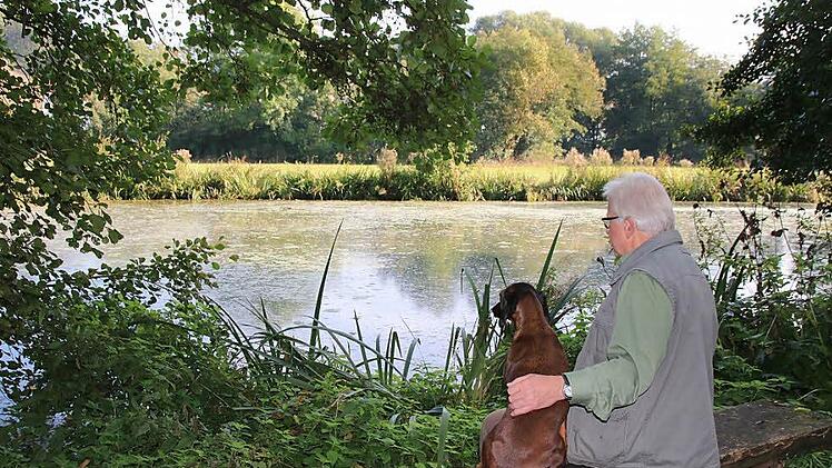 Der Eissee am Musikschulweg ist ein idyllisches Plätzchen. Von der Sitzbank aus kann Hubert Holzheimer die Tierwelt beobachten, die sich hier angesiedelt hat. Fürs Foto darf auch sein Hund Cora ausnahmsweise einmal auf die Bank. Foto: Heike Beudert