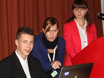 Die Geschäftsidee "Kochbuch" präsentierten bei der Hauptversammlung der Aktionäre der Vorstandsvorsitzende Patrik Lediger, Schulpatin Susanne Müller und Pressesprecherin Anna Schneider. Foto: Günther Geiling