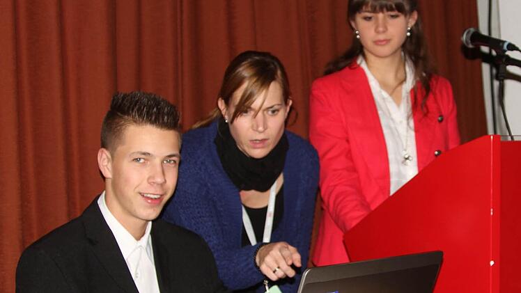 Die Geschäftsidee "Kochbuch" präsentierten bei der Hauptversammlung der Aktionäre der Vorstandsvorsitzende Patrik Lediger, Schulpatin Susanne Müller und Pressesprecherin Anna Schneider. Foto: Günther Geiling