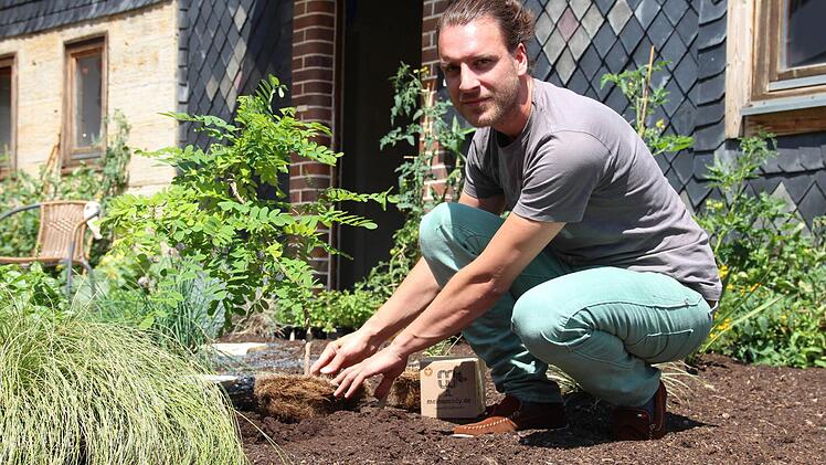 So einfach ist es einen Baum zu pflanzen. Ozan Durukan demonstriert es im kleinen Vorgarten von Bio-Benni in Witzmannsberg, der die Produkte von Seed Evolution UG auch vertreibt. Zum Angebot der Firma gehören aber auch Samen für Kräuter und Gemüse. Die Töpfe bestehen aus Kokos-, die Deckel aus Zuckerrohrfaser. Fotos: Helke Renner, privat