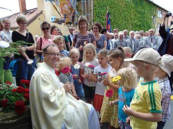 Die Weißenoher Kindergartenkinder überreichen ihrem Florian Sassik zu seiner Primiz Blumen.  Foto: Petra Malbrich