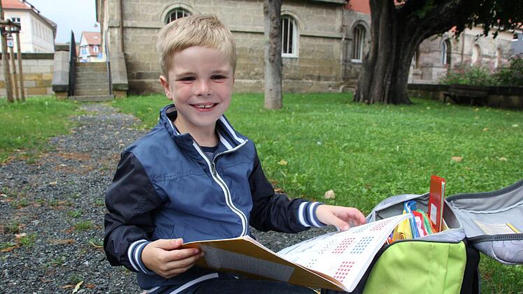 Der siebenjährige Ben Fischer blättert in seinem Arbeitsheft.