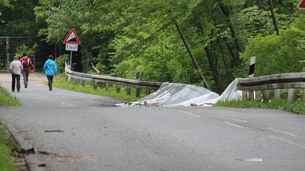 Obwohl die Kreisstra&szlig;e LIF 7 abgesperrt und mit Gittern angesichert ist, setzen sich am Sonntagmittag Neugierige &uuml;ber das Verbot hinweg und laufen die Stra&szlig;e entlang. Durch die tagelangen Regenf&auml;lle ist die Stra&szlig;e nach rechts, zum Main hin abgesackt. Im Kurvenbereich Richtung Weingarten sind B&auml;ume umgest&uuml;rzt oder drohen, auf die Fahrbahn zu fallen. Fotos: Matthias Einwag