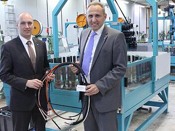 Delfingen-Juniorchef Gérald Streit (links) und Geschäftsführer Matthias Littig mit einigen durch textile Flechtsysteme geschützten Kabeln vor einer der Flechtmaschinen in Marktrodach  Fotos: Friedwald Schedel