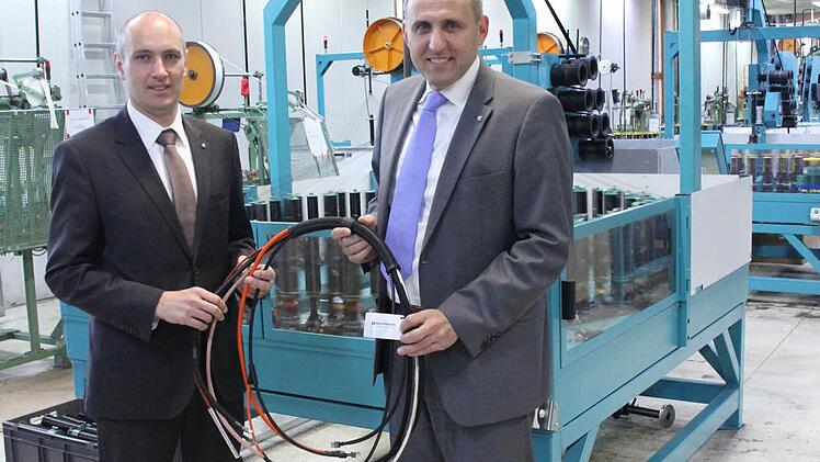Delfingen-Juniorchef Gérald Streit (links) und Geschäftsführer Matthias Littig mit einigen durch textile Flechtsysteme geschützten Kabeln vor einer der Flechtmaschinen in Marktrodach  Fotos: Friedwald Schedel