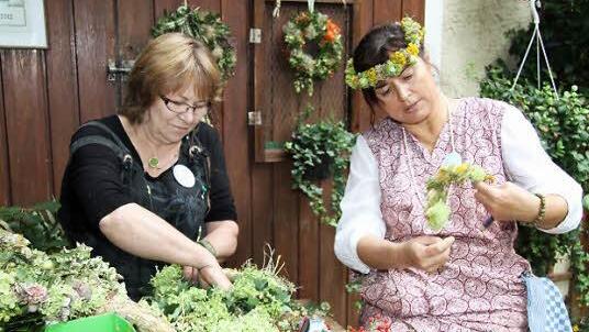 Waltraud Lieb und Marianne Mahr flechten Blumenkränze.