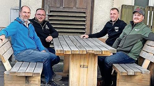 Bürgermeister Holger Schmitt (von links), Kommandant Bastian Wehner, Vorsitzender Heiko Dünisch und Revierleiter André Schönfeldt testen die neue Bank.
