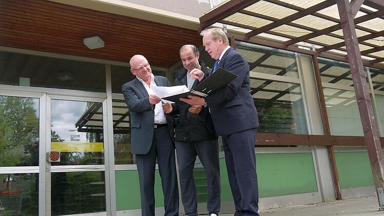 Auf dem Papier schaut das Konzept des "Dorfladens" für Kaltenbrunn schon ganz gut aus - finden (von links) Dieter Scherbel, Jony Salameh und Werner Thomas. Im Hintergrund: Der ehemalige "nah und gut", der mit seinen 330 Quadratmetern Verkaufsfläche für das Projekt in Frage kommen könnte. Foto: Berthold Köhler