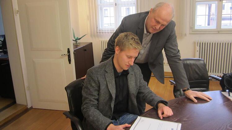 David Spenger (links) &uuml;bergibt B&uuml;rgermeister Gerald Brehm einen Abzug seiner Bachelorarbeit, die sich mit dem Karpfenland besch&auml;ftigt.  Foto: Filiz Mailhammer