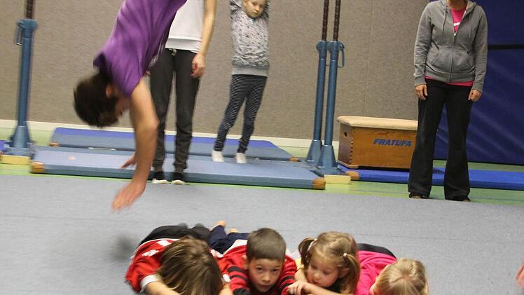 Jan mit einem Salto über vier Kids, hinten Trainerin Fabiola DiBiasi. Foto: Gerd Ludwig
