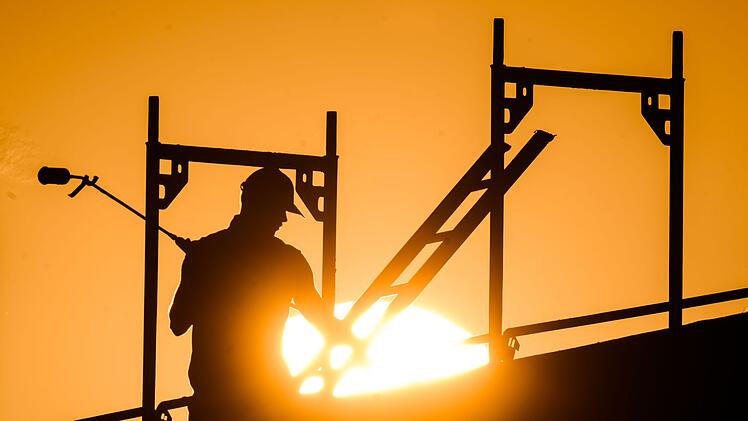 Ein Bauarbeiter im Gegenlicht der Sonne auf einem Ger&uuml;st