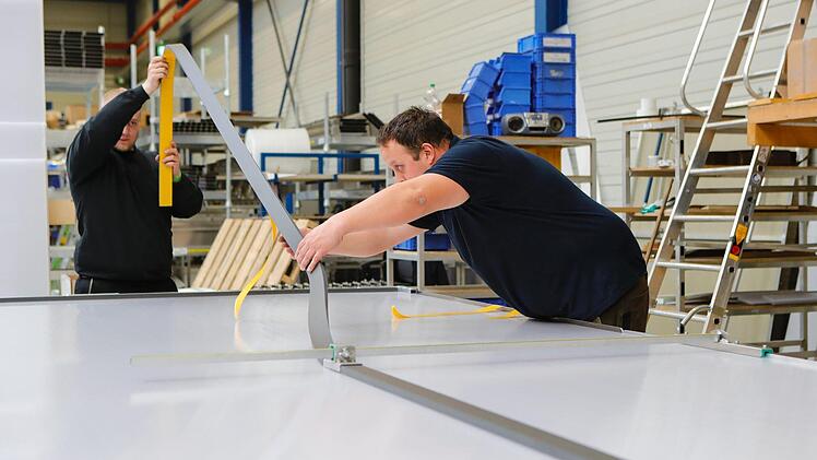 Sparte Tageslichtsysteme: Mitarbeiter bearbeiten eine große Polycarbonatglasplatte. Foto: Matthias Hoch