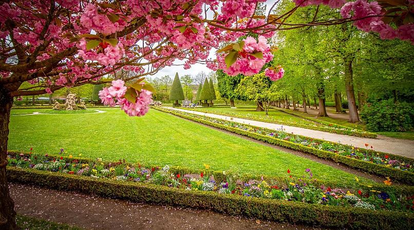 Kunstvolle Skulpturen, symmetrische Blumenbeete und schattige Laubeng&auml;nge laden zum Flanieren im Hofgarten der W&uuml;rzburger Residenz ein.