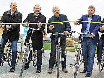 Das Eröffnungsband des Auenwegs, der die Kreise Lichtenfels und Bamberg verbindet, schneiden Politiker aus beiden Kreisen gemeinsam durch (von links): Landrat Christian Meißner (Lichtenfels), Landrat Hans Kalb (Bamberg), Bürgermeister Bernhard Storath (Ebensfeld), MdB Andreas Schwarz und Bürgermeister Jürgen Kohmann (Bad Staffelstein). Anschließend radelten sie die ersten 1,5 Kilometer bis nach Niederau. Foto: Matthias Einwag