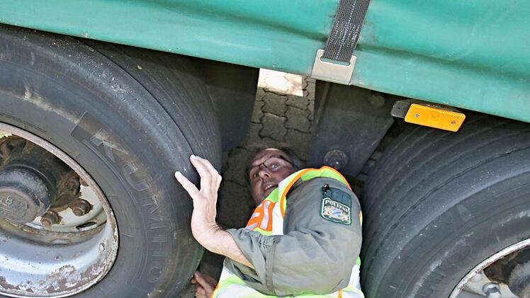 Achim Seufert von der Polizei-Inspektion Ebern "gibt alles": Er zwängt sich zwischen zwei Reifen unter den Lkw, um die Bremszylinder zu kontrollieren, weil er feststellte, dass die Nabe des linken Reifens brennend heiß war.Helmut  Will