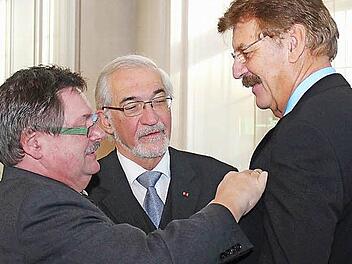 Staatssekretär Gerhard Eck (links) verleiht Reimar Glückler (rechts) im Beisein von Regierungspräsident Paul Beinhofer das Bundesverdienstkreuz. Foto: Johannes Hardenacke/ Regierung von Unterfranken