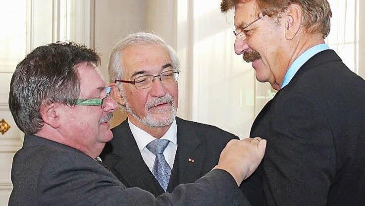 Staatssekretär Gerhard Eck (links) verleiht Reimar Glückler (rechts) im Beisein von Regierungspräsident Paul Beinhofer das Bundesverdienstkreuz. Foto: Johannes Hardenacke/ Regierung von Unterfranken