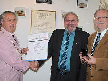 Robert Schmitt, Obermeister der Metzgerinnung, überreicht Oswald Hüfner den Goldenen Meisterbrief. Der Geschäftsführer der Innung Winfried Schmitt hält die Ehrennadel in Gold bereit.  Fotos: Ulrike Müller