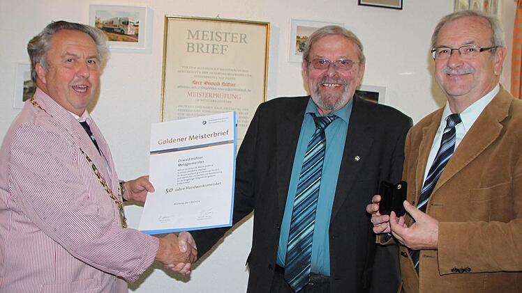 Robert Schmitt, Obermeister der Metzgerinnung, überreicht Oswald Hüfner den Goldenen Meisterbrief. Der Geschäftsführer der Innung Winfried Schmitt hält die Ehrennadel in Gold bereit.  Fotos: Ulrike Müller