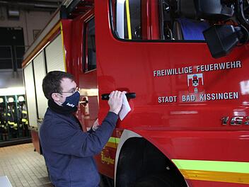 Marco Albert, der Gerätewart der Bad Kissinger Feuerwehr desinfiziert die Türgriffe der Einsatzfahrzeuge. Foto: Johannes Schlereth