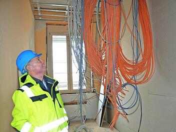 Stadtratsmitglied Heinz Pommer betrachtet die Kabel, die im künftigen Server-Raum der Mittelschule von der Decke hängen. Foto: Rainer Lutz